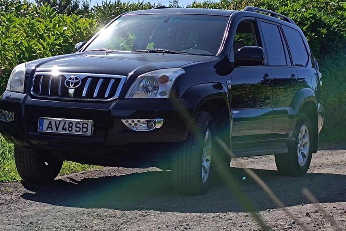 sebuah SUV biru terparkir di jalan tanah