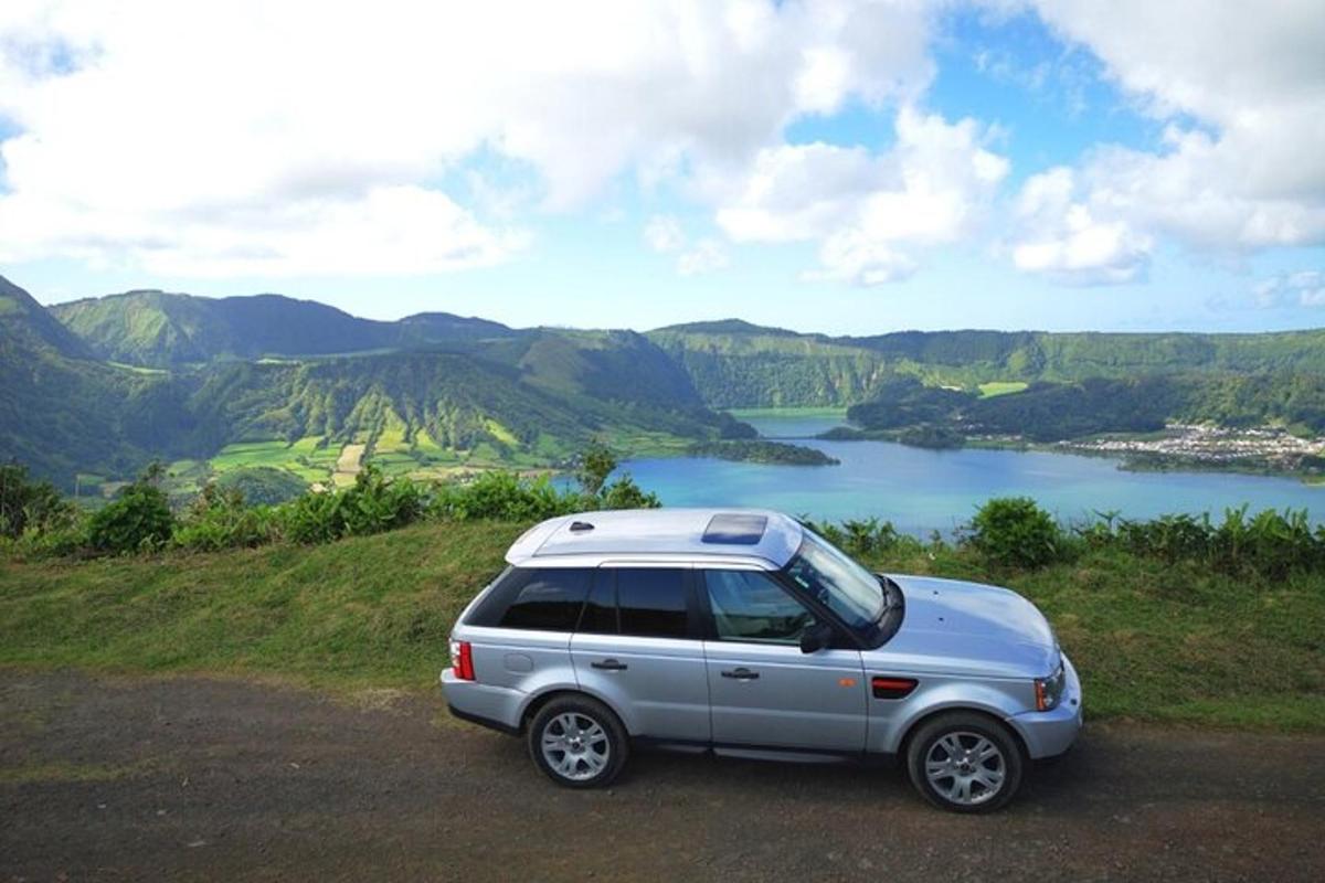 sebuah SUV berwarna perak diparkir di atas bukit yang menghadap ke danau