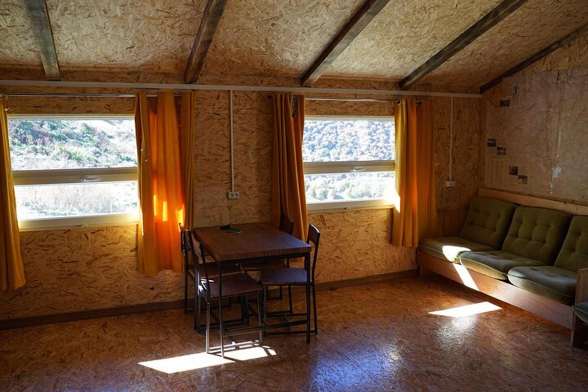 a room with a table and a couch and two windows