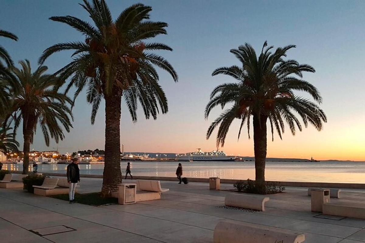ein Strand mit Palmen und Menschen, die auf einem Bürgersteig spazieren gehen