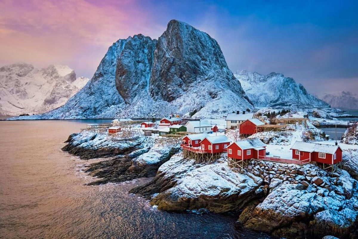 a group of houses on a rocky island with snow covered mountains