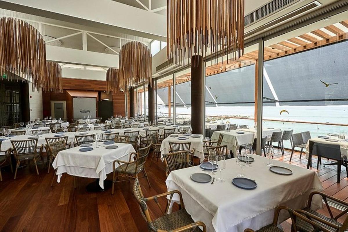 Un restaurante con mesas y sillas blancas y un gran ventanal.