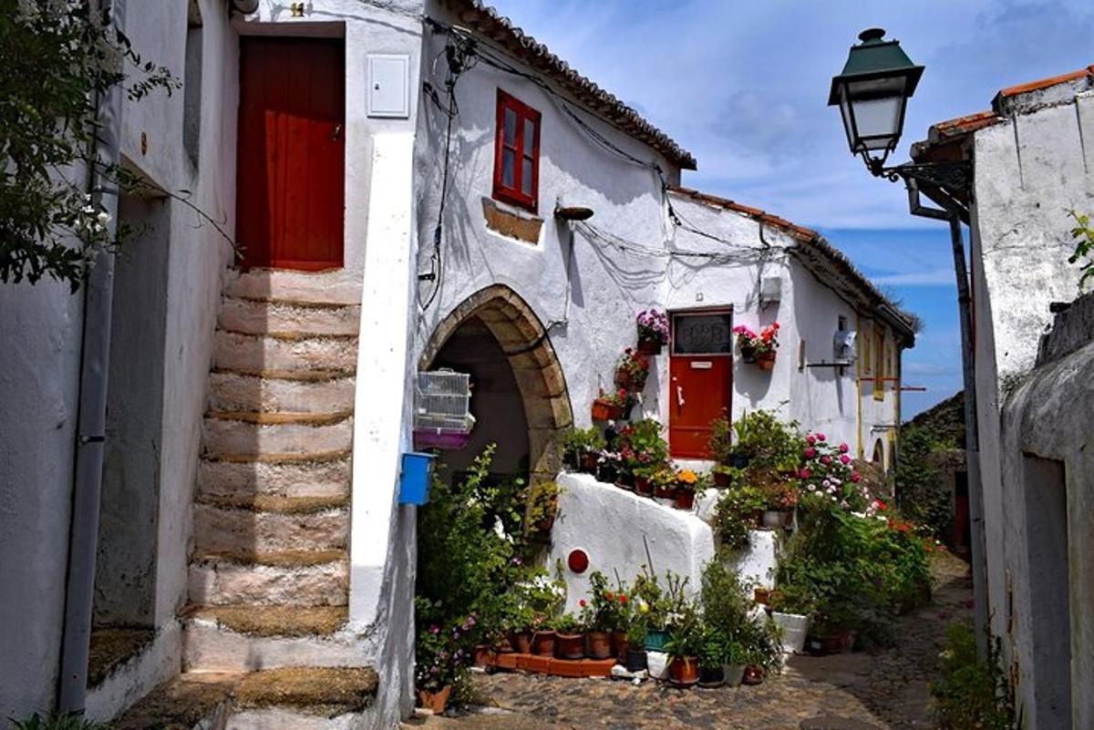 an alley with white buildings with red doors and flowers