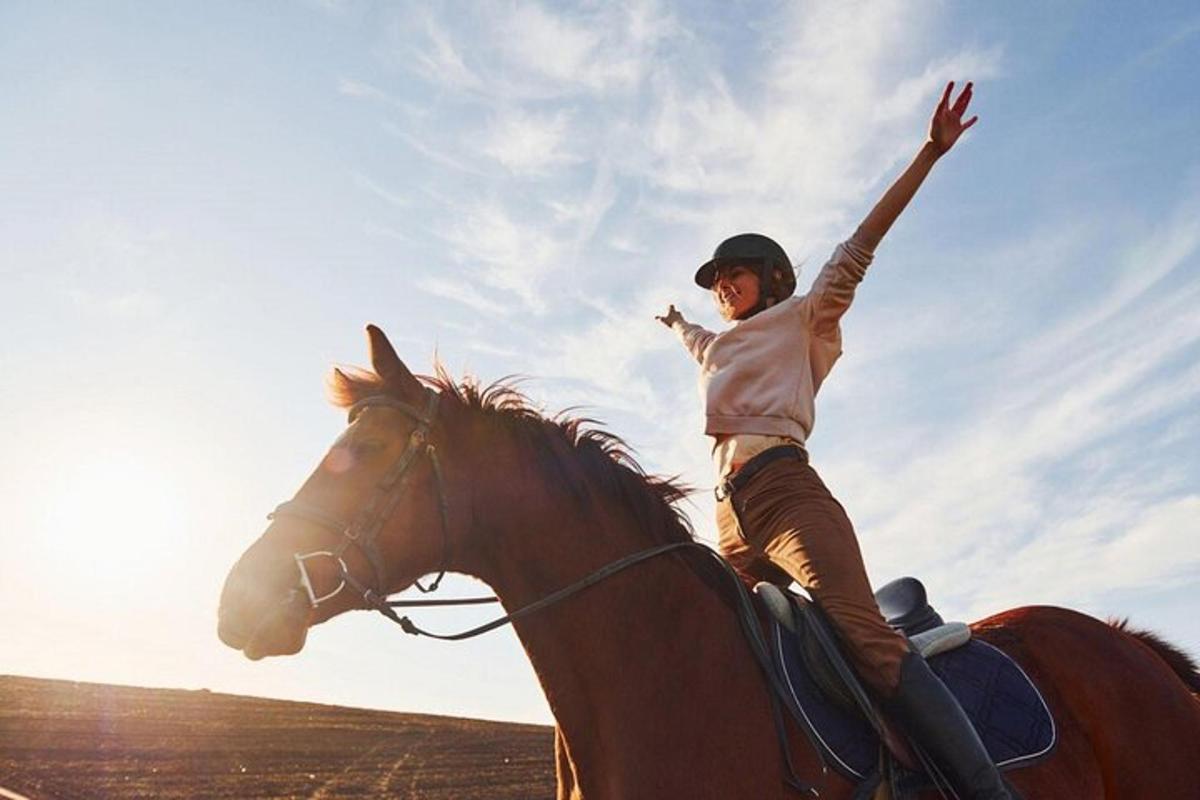 a woman riding a horse with her arms in the air