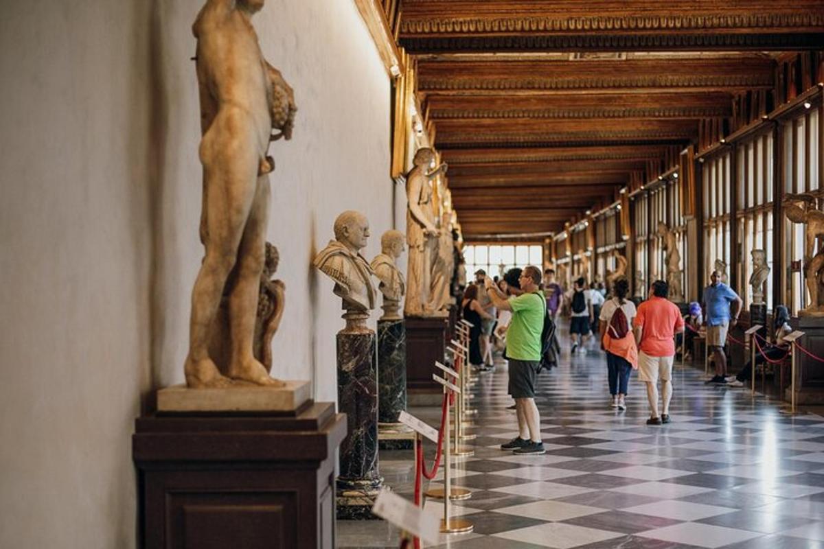 Personas caminando por un pasillo con estatuas en un museo.