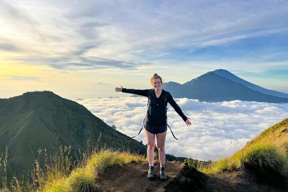 žena stojící na vrcholu hory s rozpaženýma rukama
