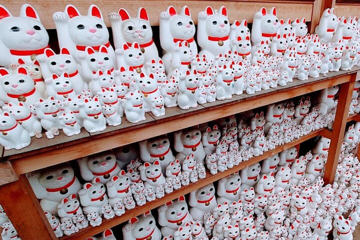 een tentoonstelling van witte kattenbeeldjes op een plank