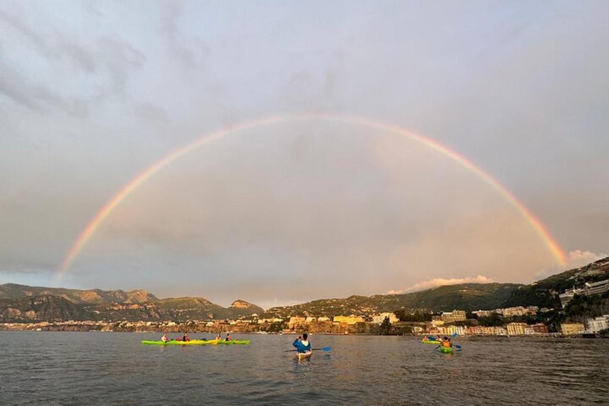 pelangi di atas badan air dengan orang di dalam kayak