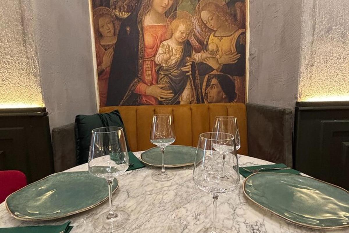 Una mesa con copas de vino y un cuadro en la pared.