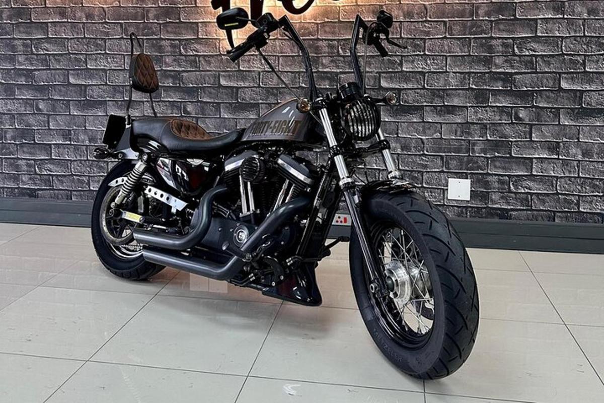 a black motorcycle parked in front of a brick wall