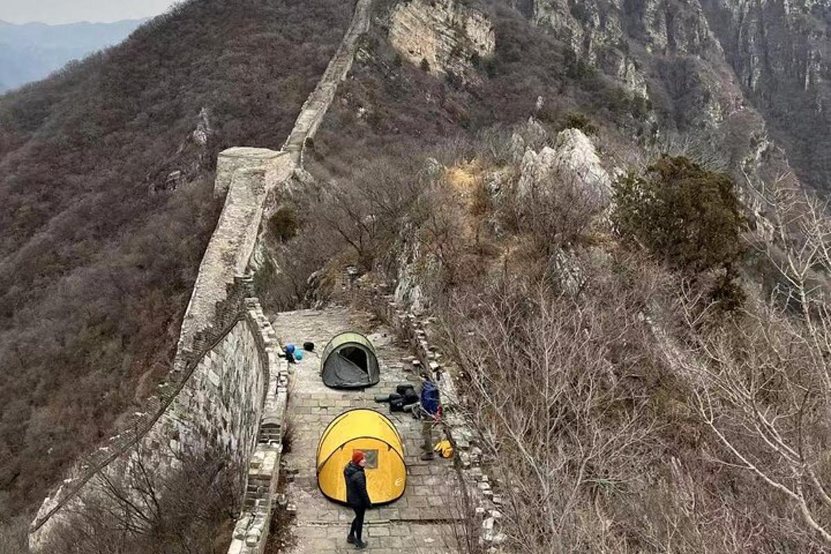 una persona con un ombrello giallo che cammina sulla grande muraglia