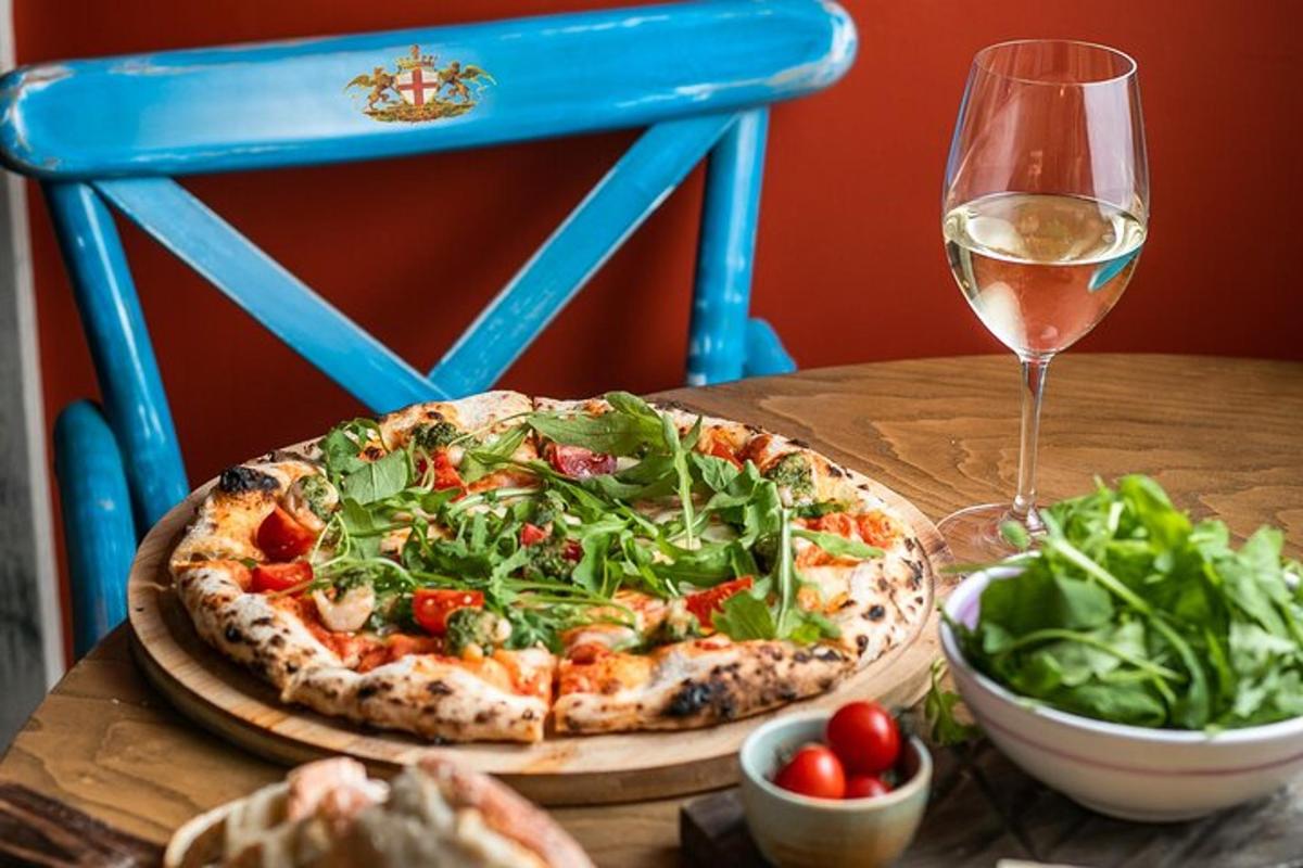 a pizza and a salad on a table with a glass of wine