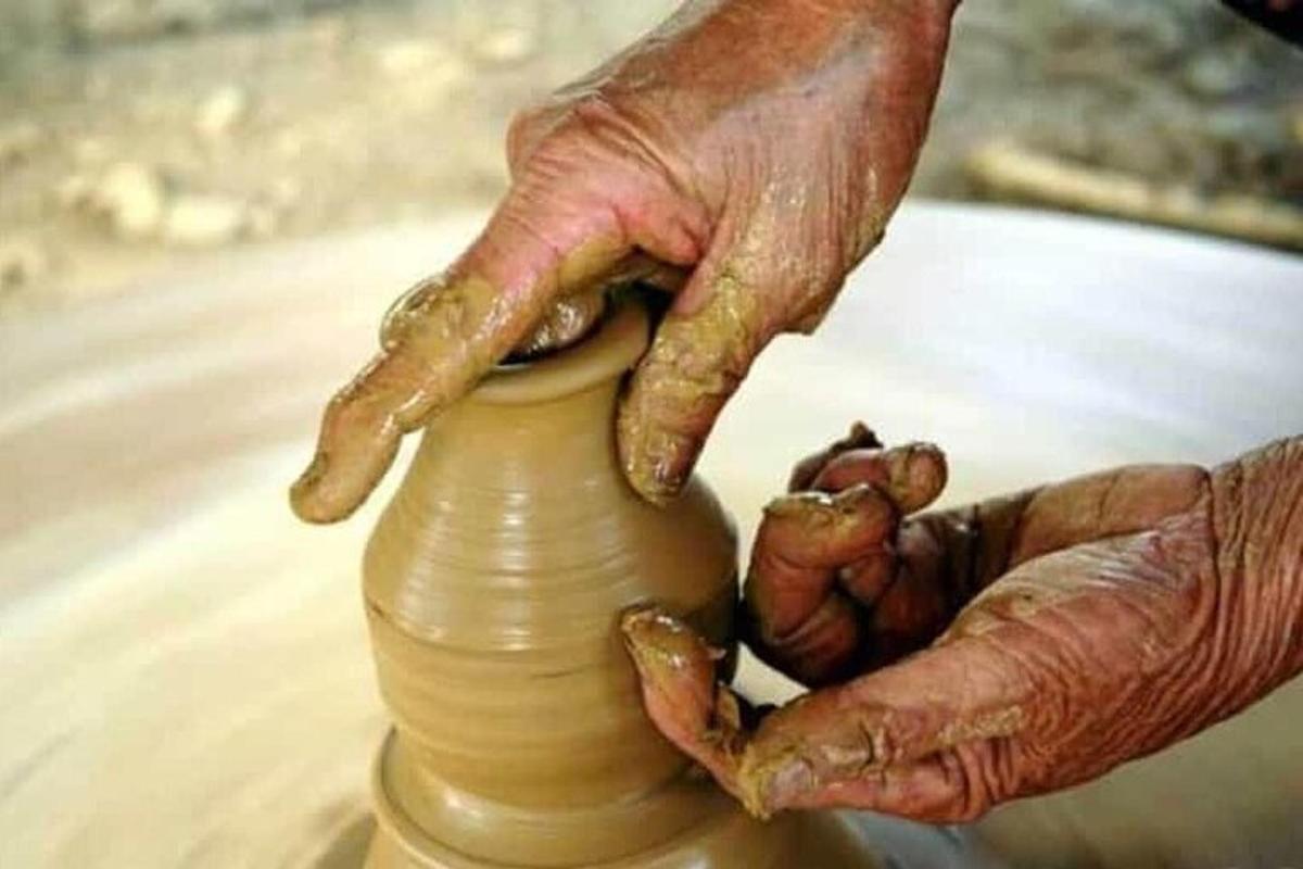 osoba vyrábějící vázu na hrnčířském kruhu