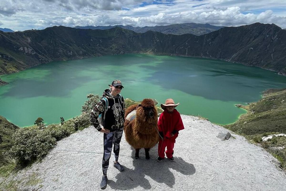 two people standing next to a llama on top of a mountain