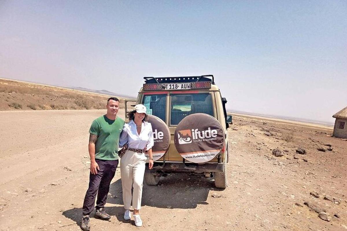 a man and a woman standing in front of a vehicle