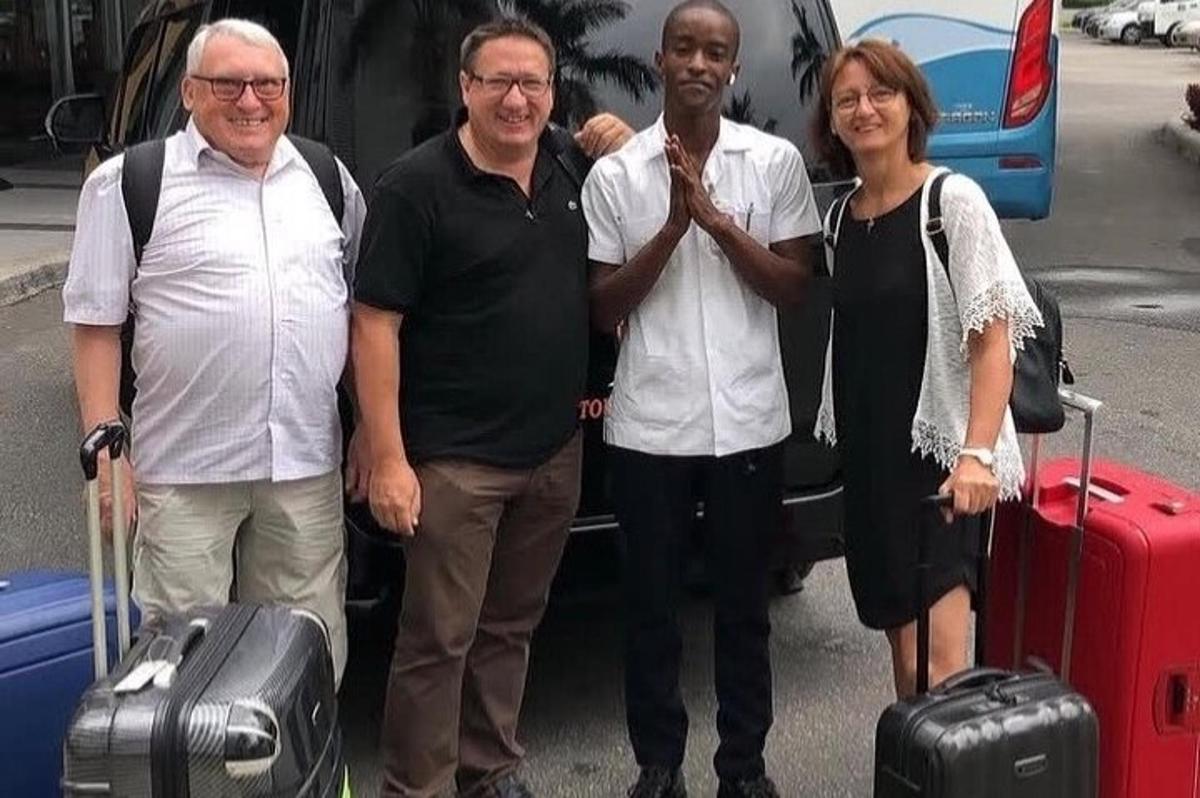 un gruppo di persone in piedi davanti a un'auto con i bagagli