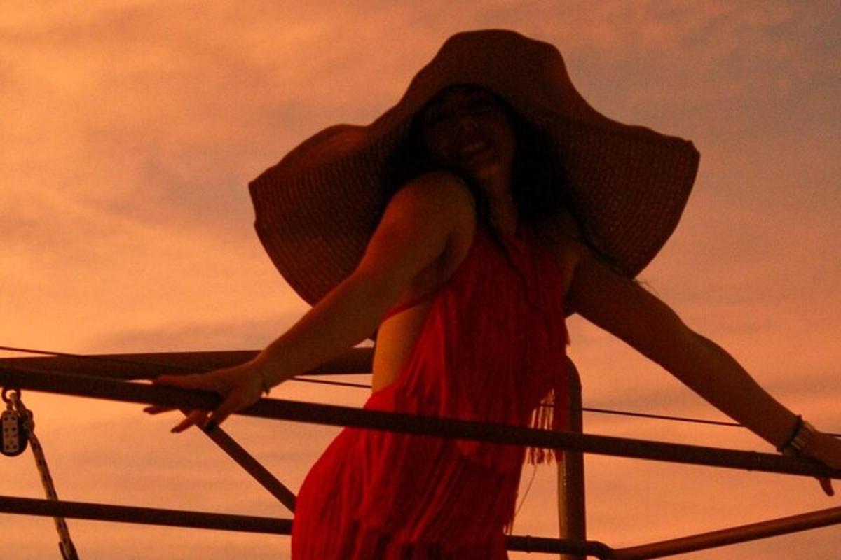 a woman wearing a floppy hat standing on a boat