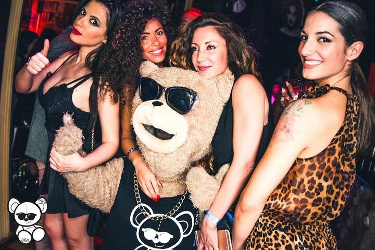Un grupo de mujeres de pie junto a un oso de peluche.