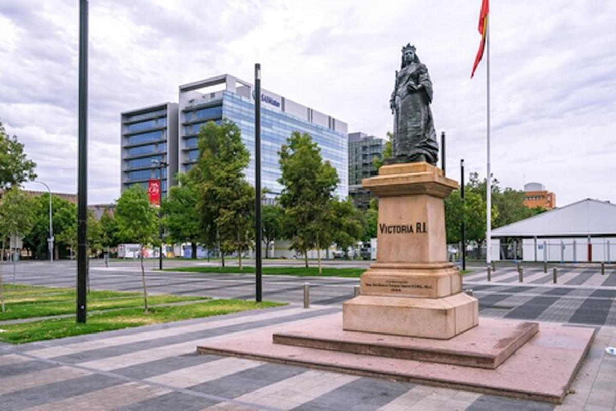 egy szobor egy tér közepén egy épülettel