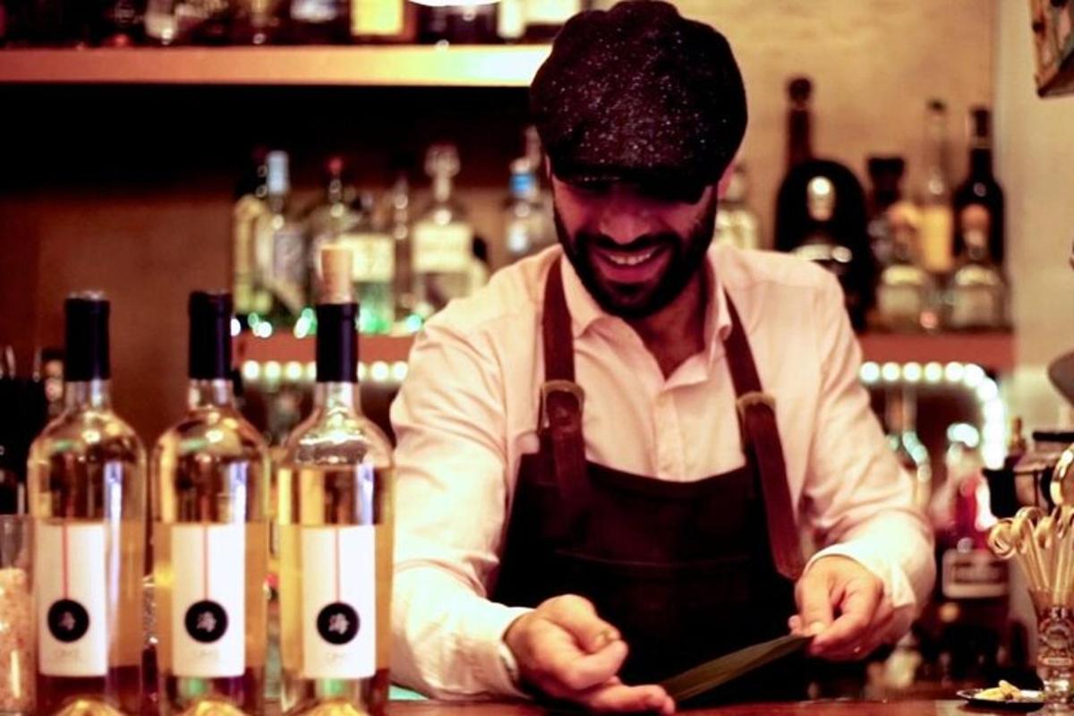 một người đàn ông đứng sau quầy bar với những chai rượu