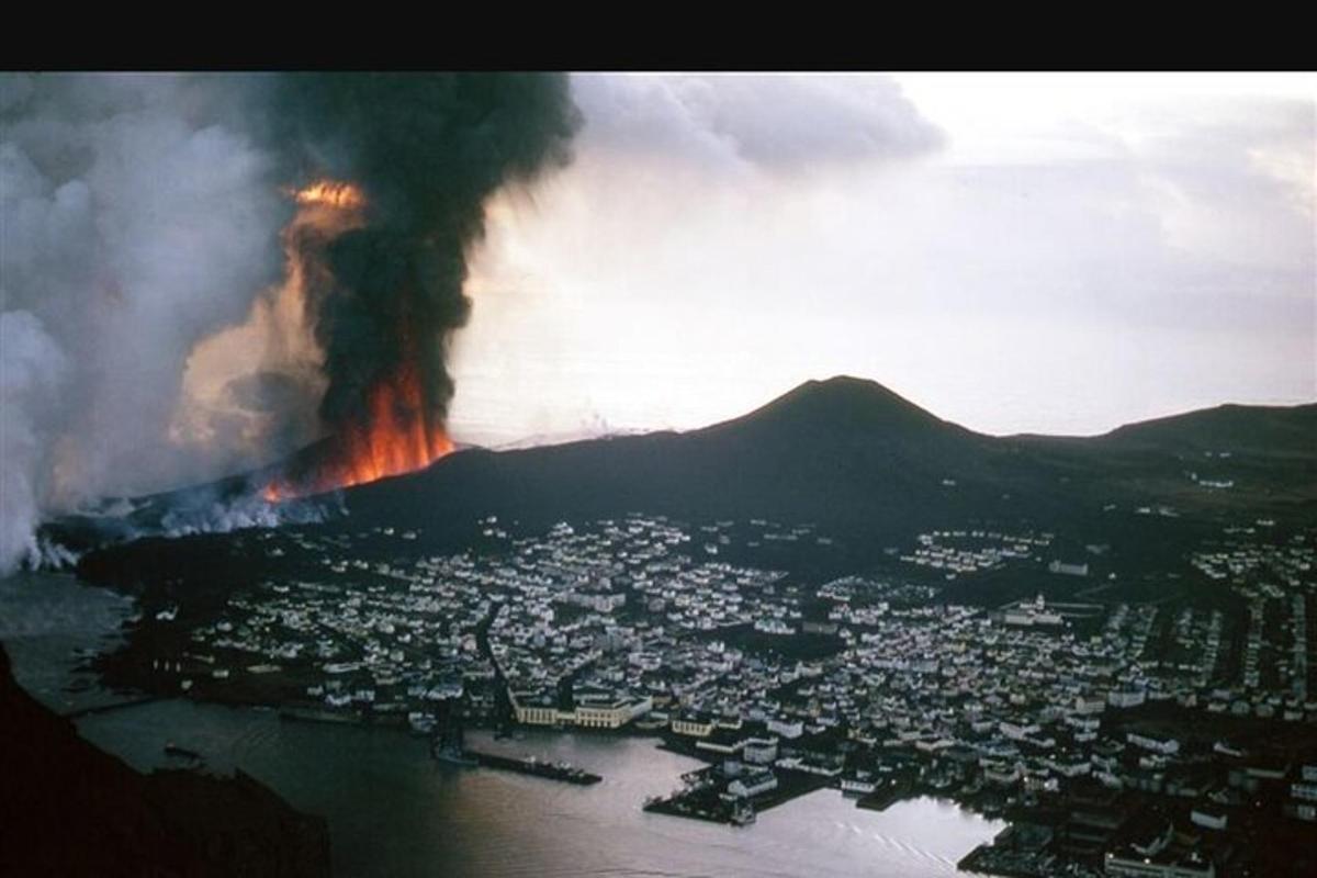 an aerial view of a erupting volcano with a city