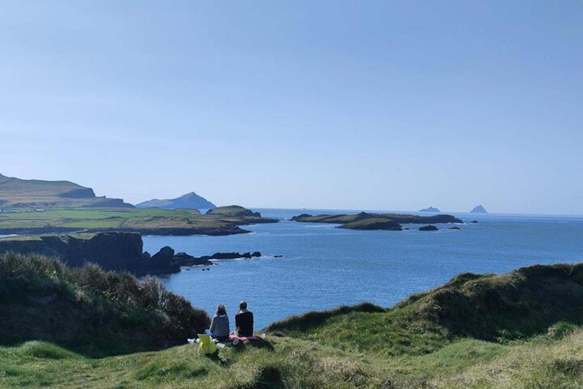 two people sitting on a hill overlooking a body of water
