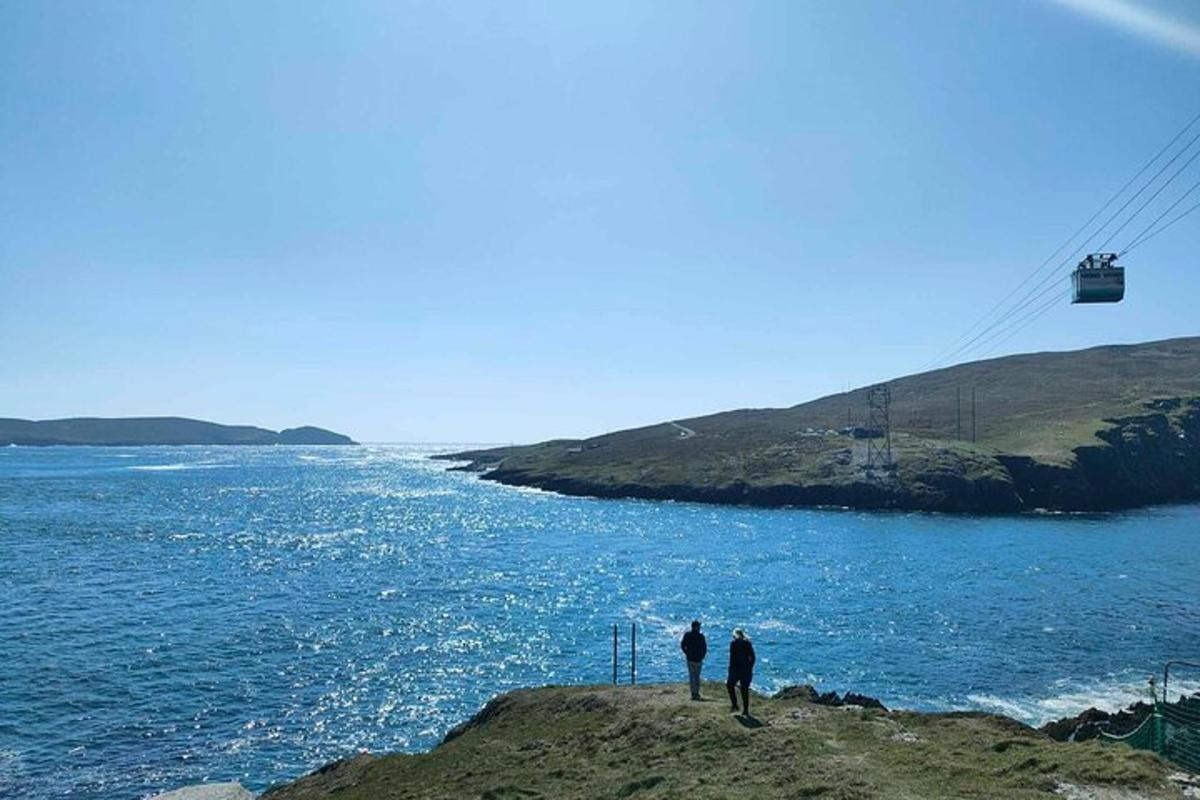 dva lidé stojící na okraji útesu s výhledem na oceán