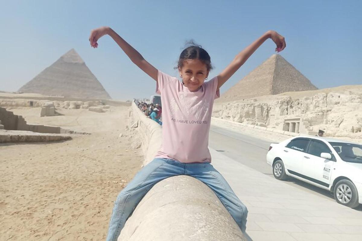 a young girl sitting on a pipe in front of the pyramids