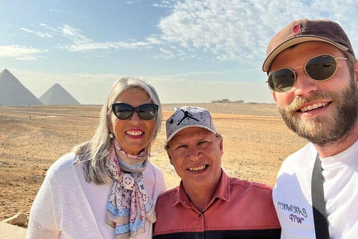 tři lidé pózují pro fotografii před pyramidami