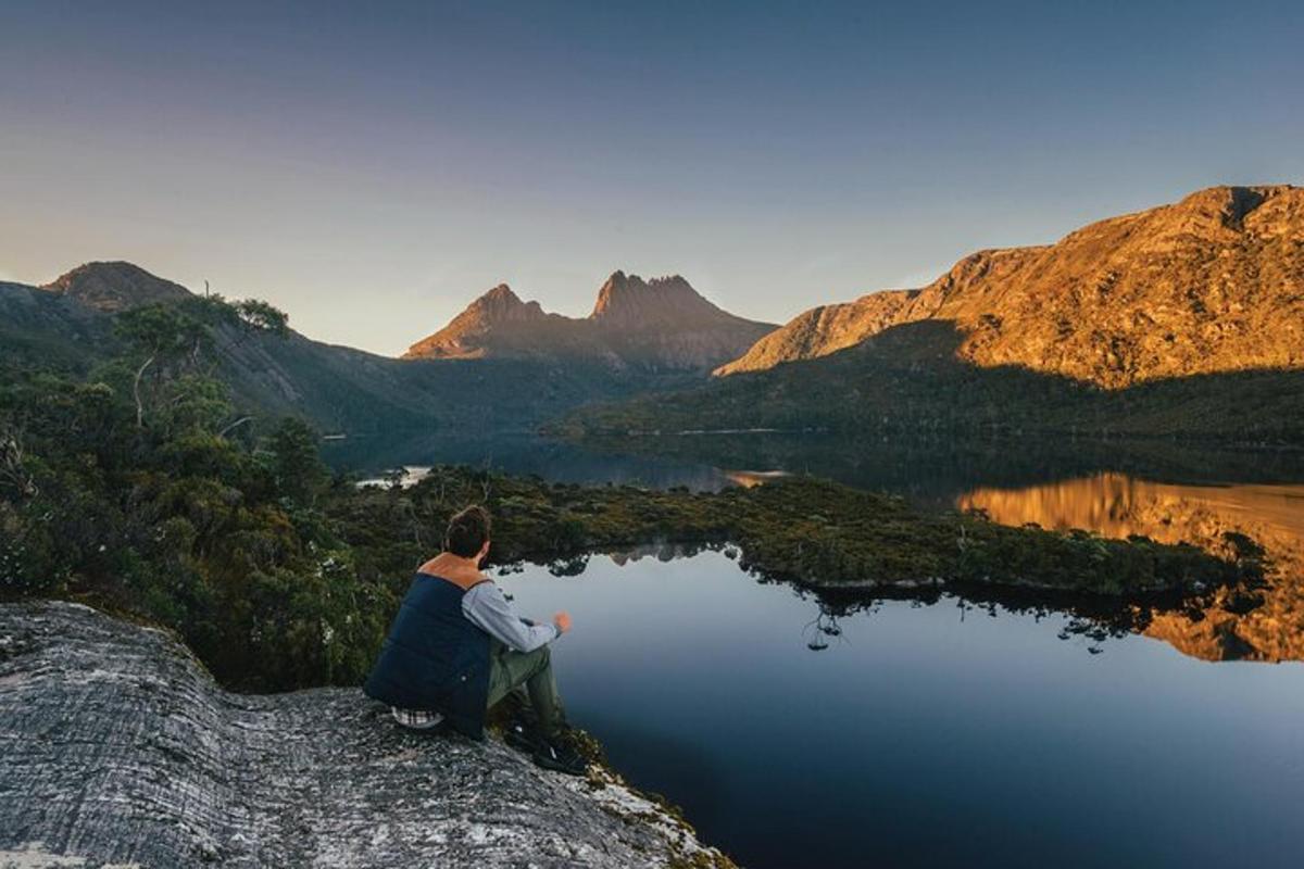 uma pessoa sentada no topo de uma rocha com vista para um lago