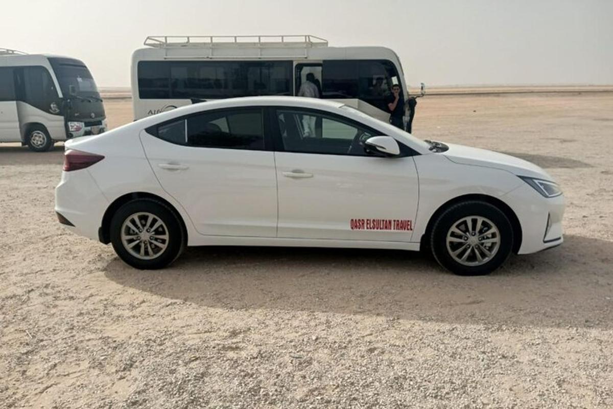 a white car parked in front of a bus