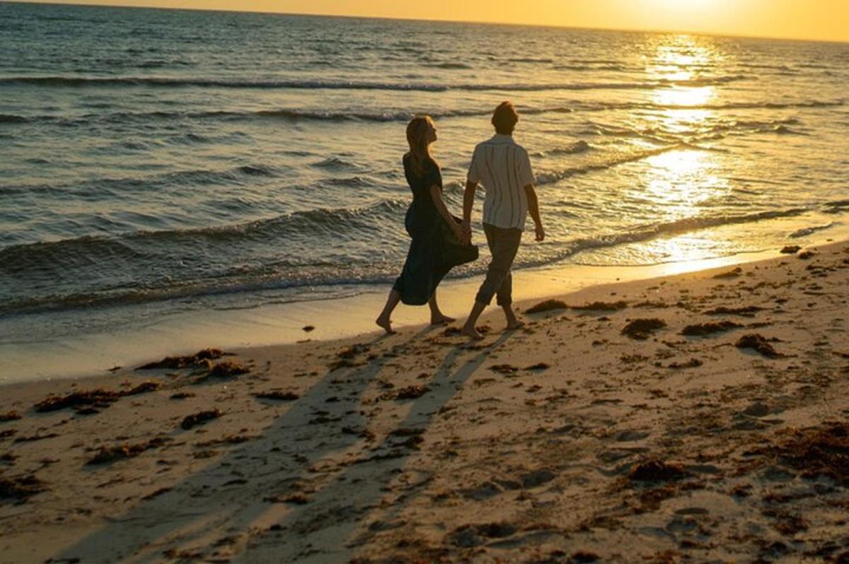 um homem e uma mulher caminhando na praia