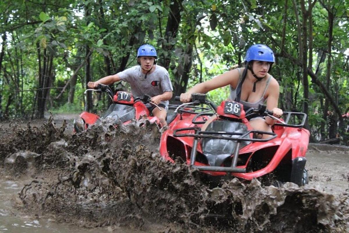 two people riding on atvs in the mud