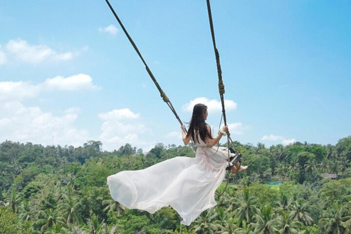 seorang wanita berpakaian putih berayun di atas buaian tali