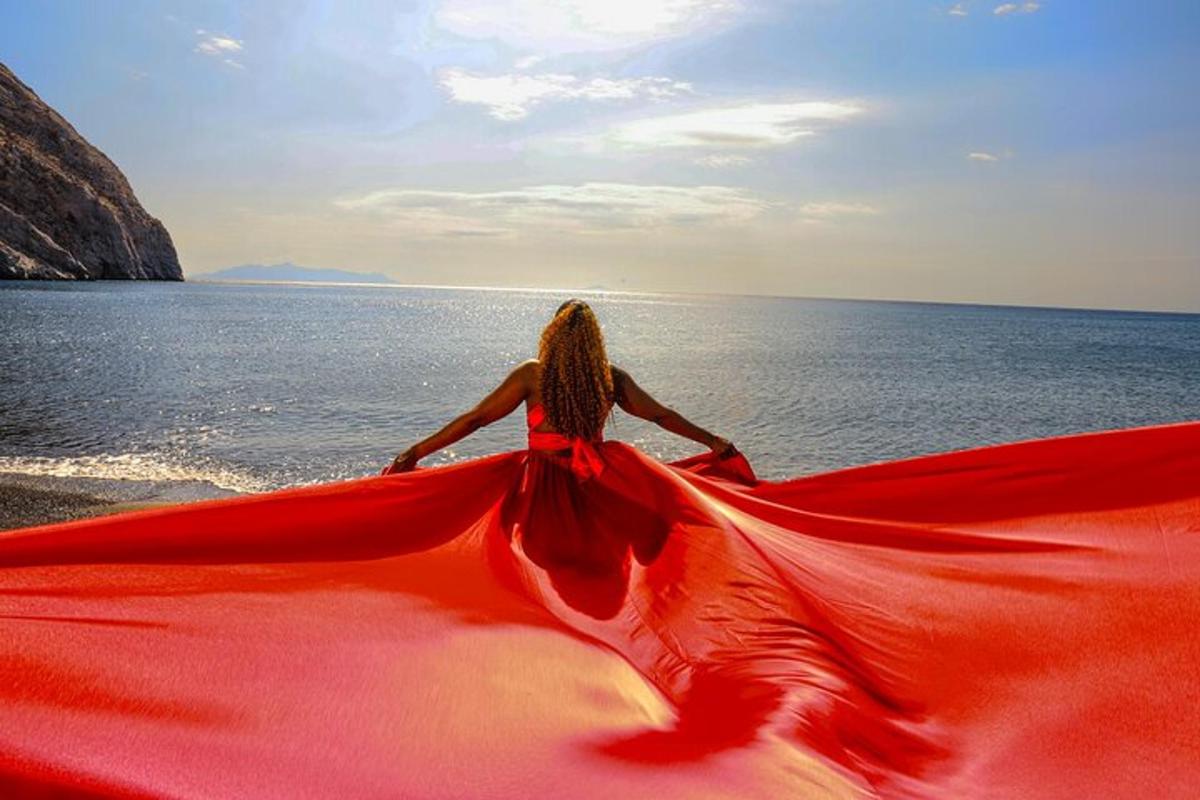 una donna in un vestito rosso seduta sulla spiaggia