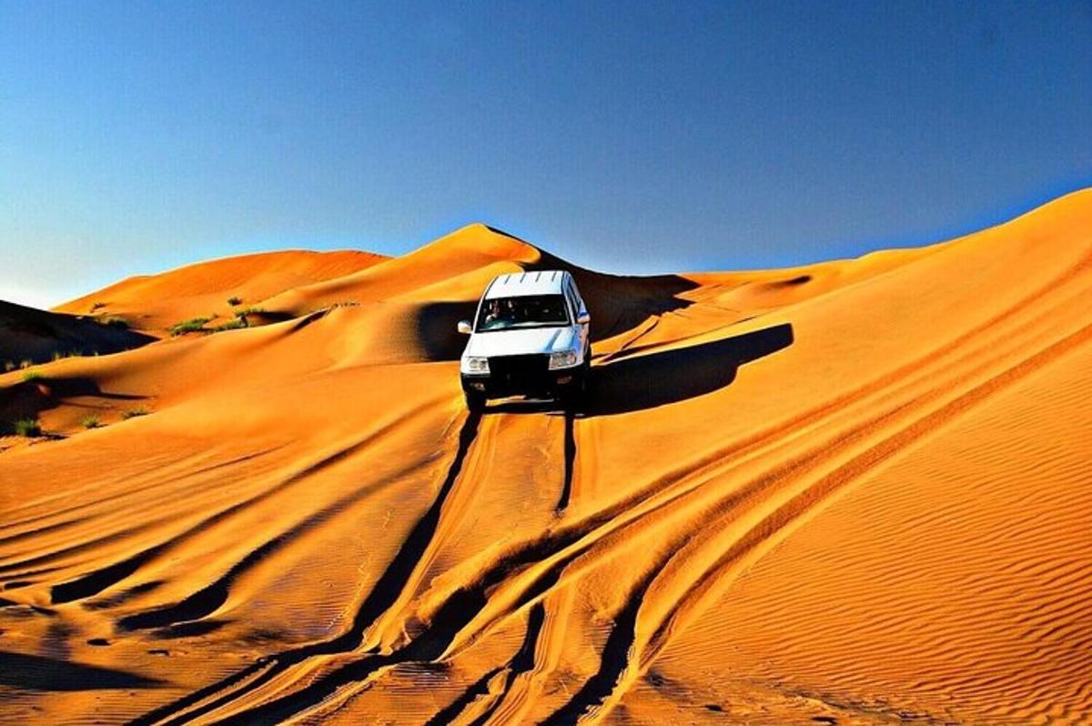 um carro branco estacionado no topo de uma duna de areia