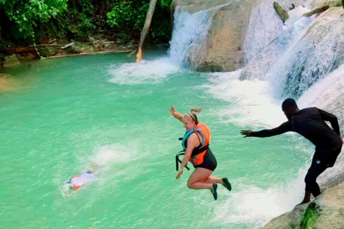 ein Mann und eine Frau im Wasser in der Nähe eines Wasserfalls