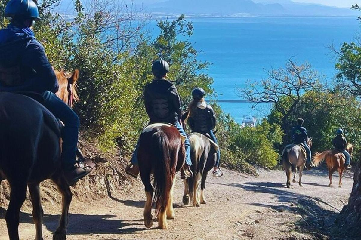 група људи која јаше коње низ земљани пут