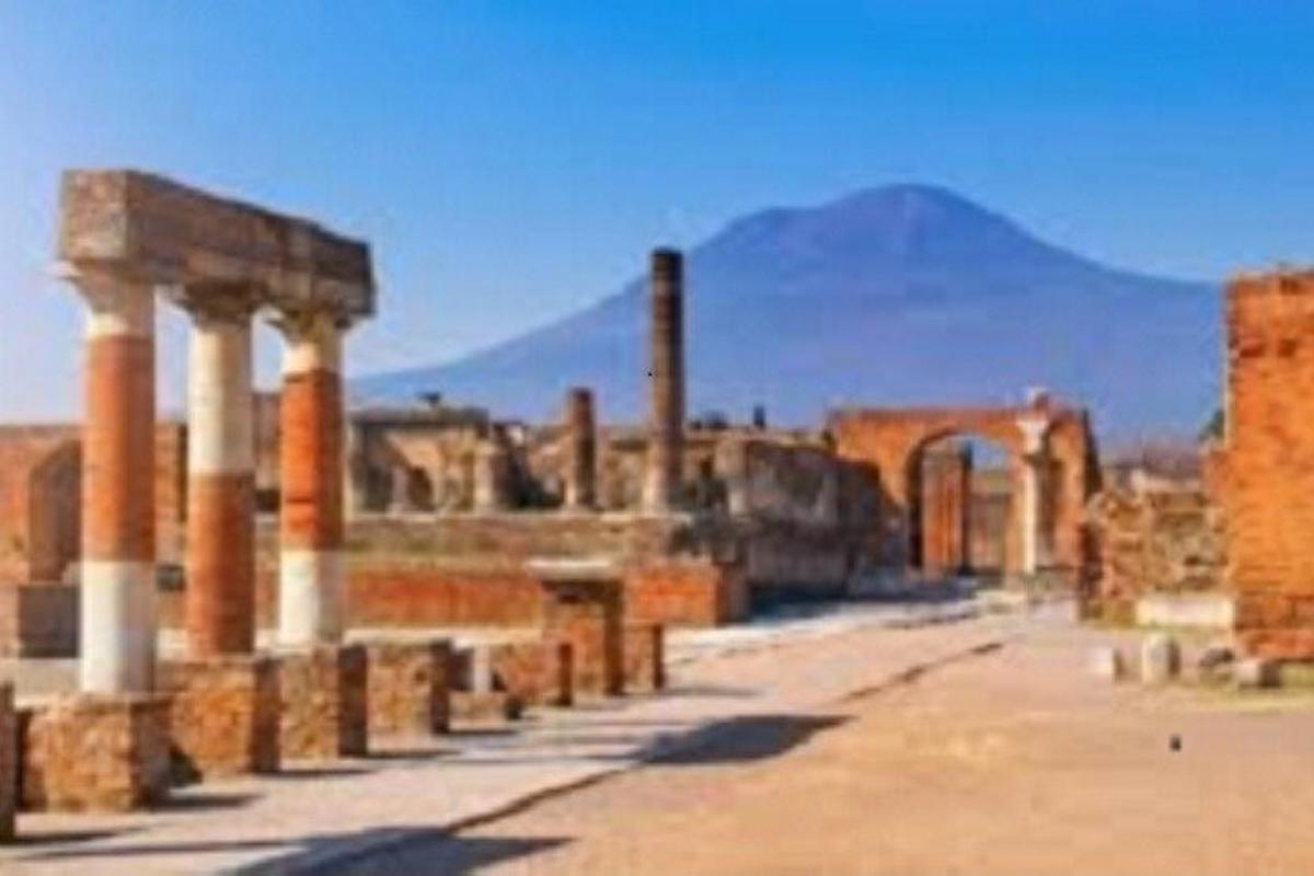Una ciudad antigua con columnas y una montaña al fondo.