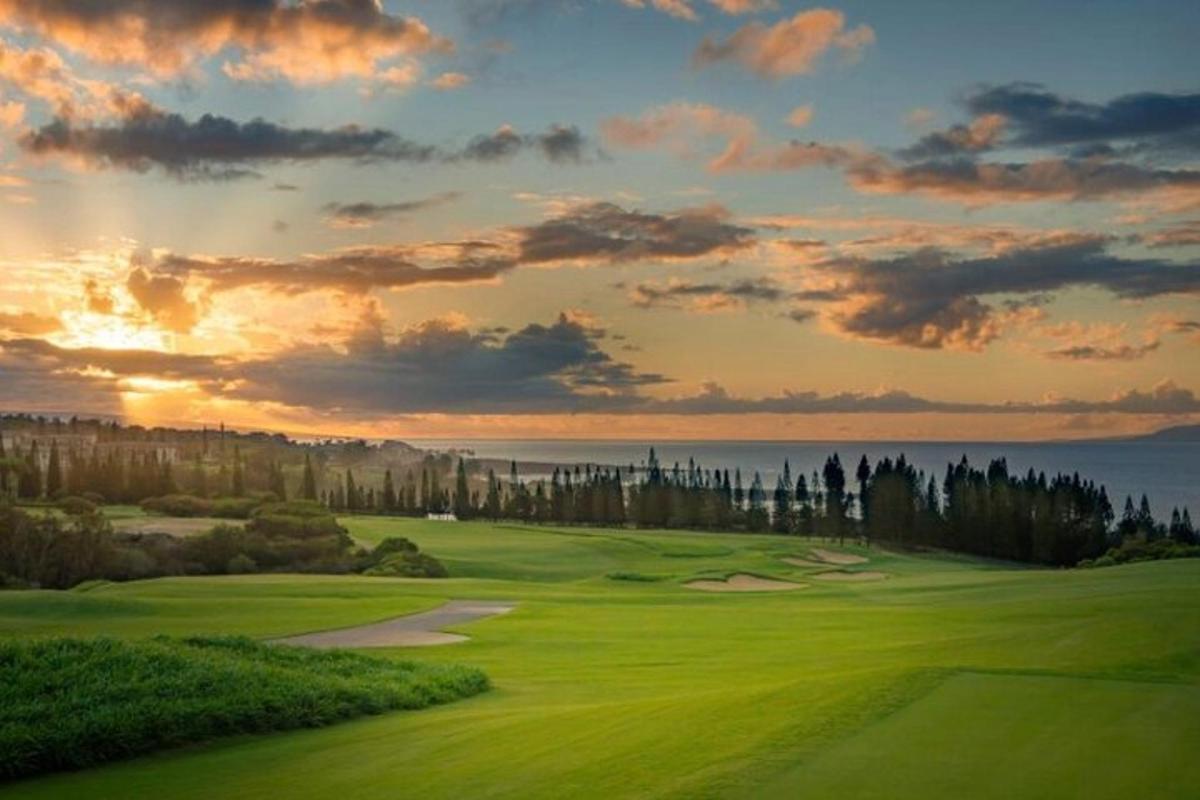 un teren de golf cu un apus de soare în fundal
