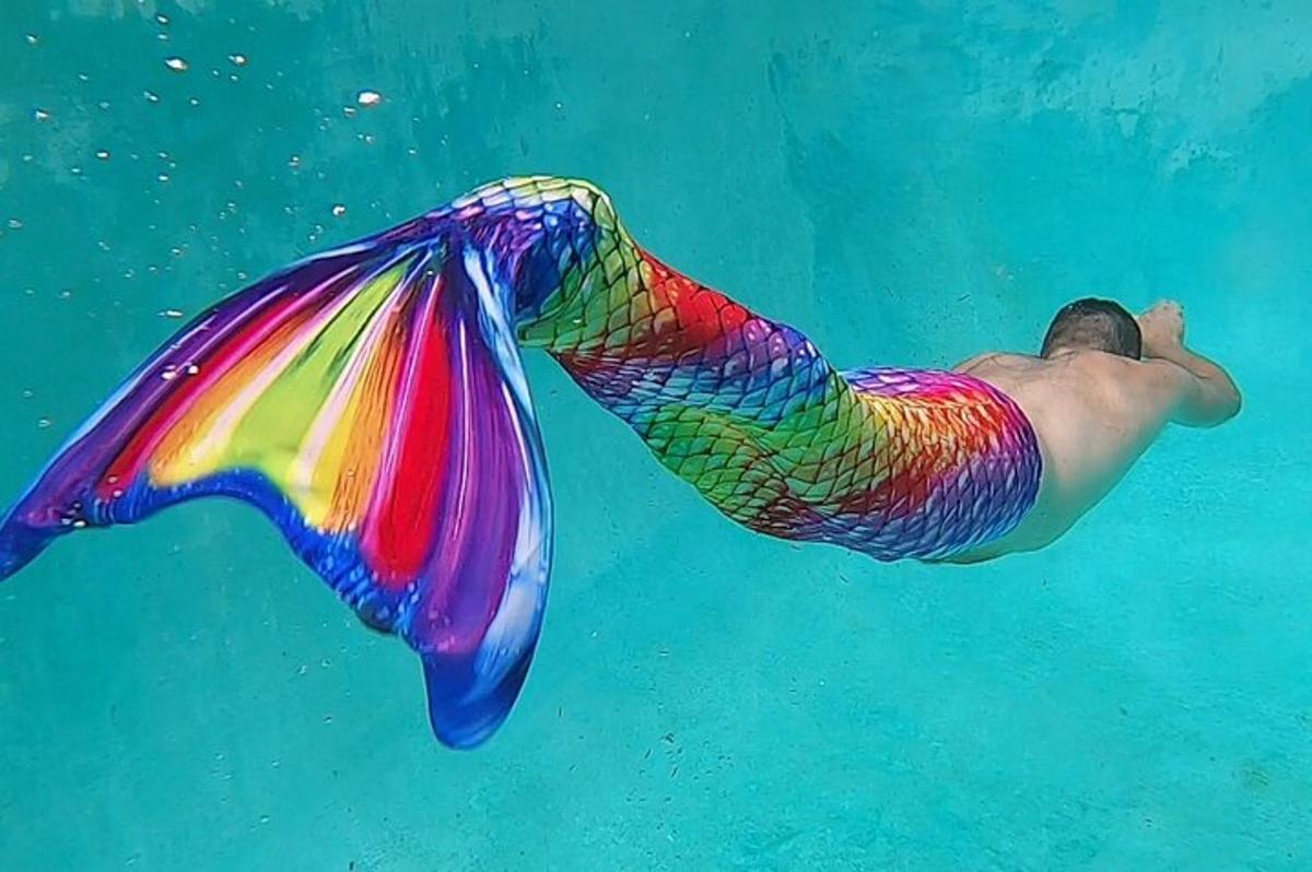 人魚の尾を付けて水中を泳ぐ男性