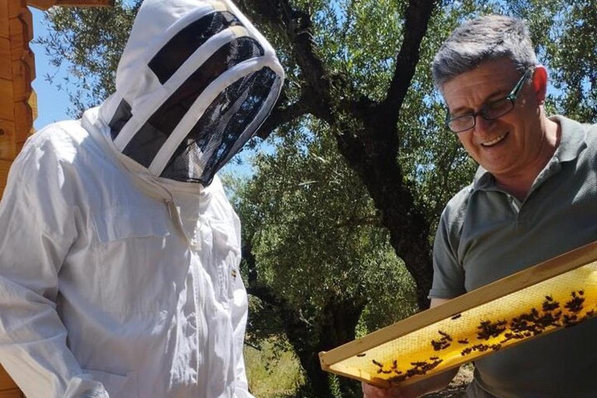 un bărbat care stă lângă o statuie a unei persoane care ține o bucată de lemn