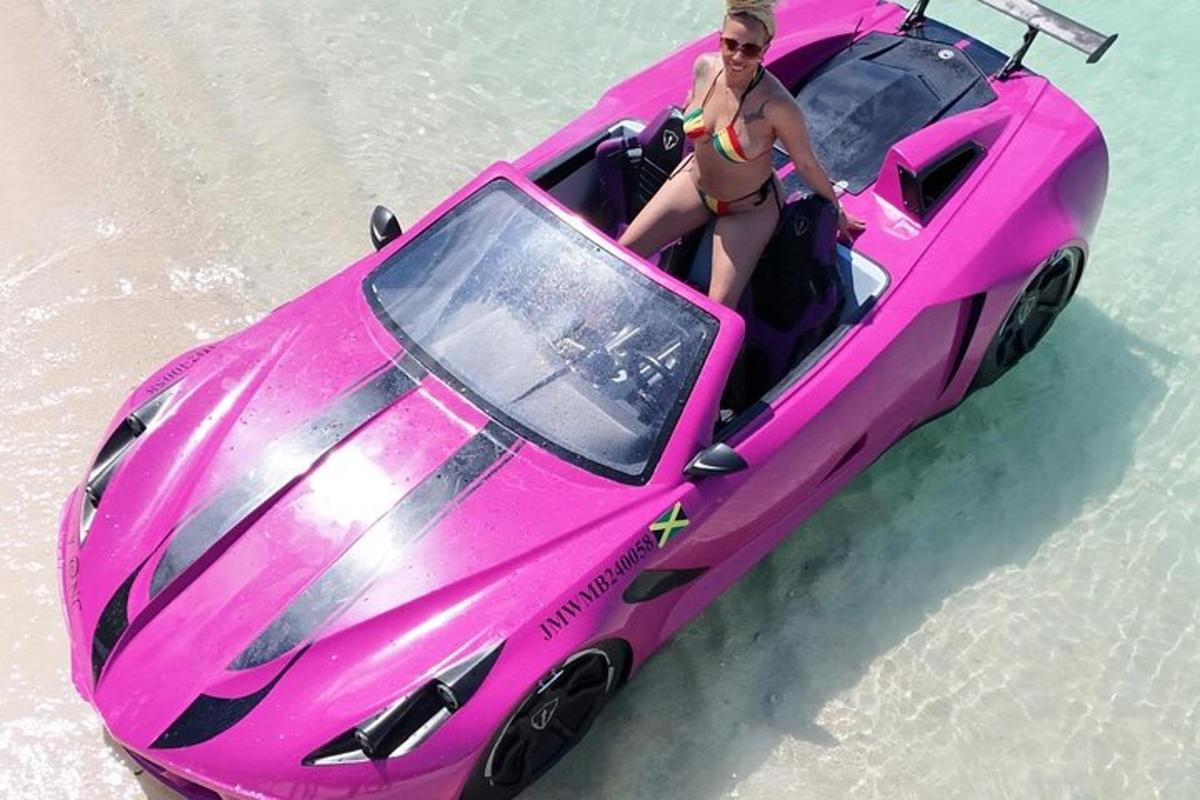 Una mujer en bikini parada en un auto rosa en el agua.