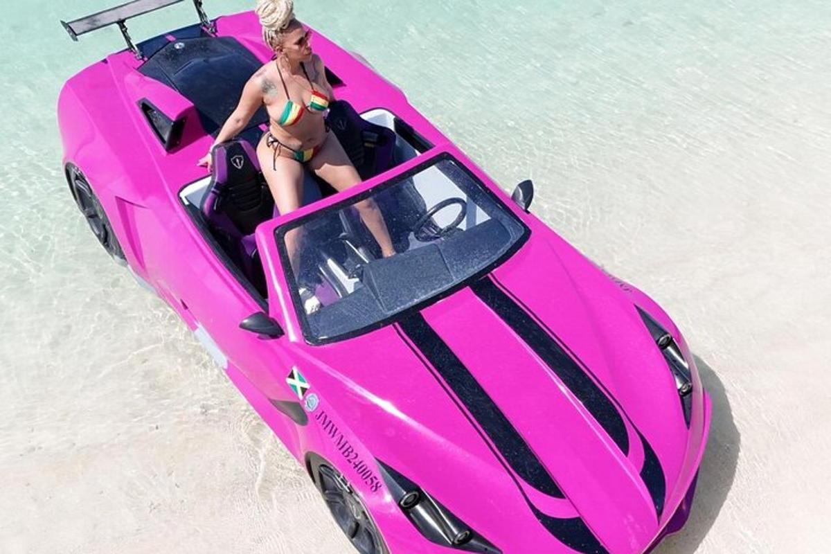 una mujer en un coche rosa en la playa