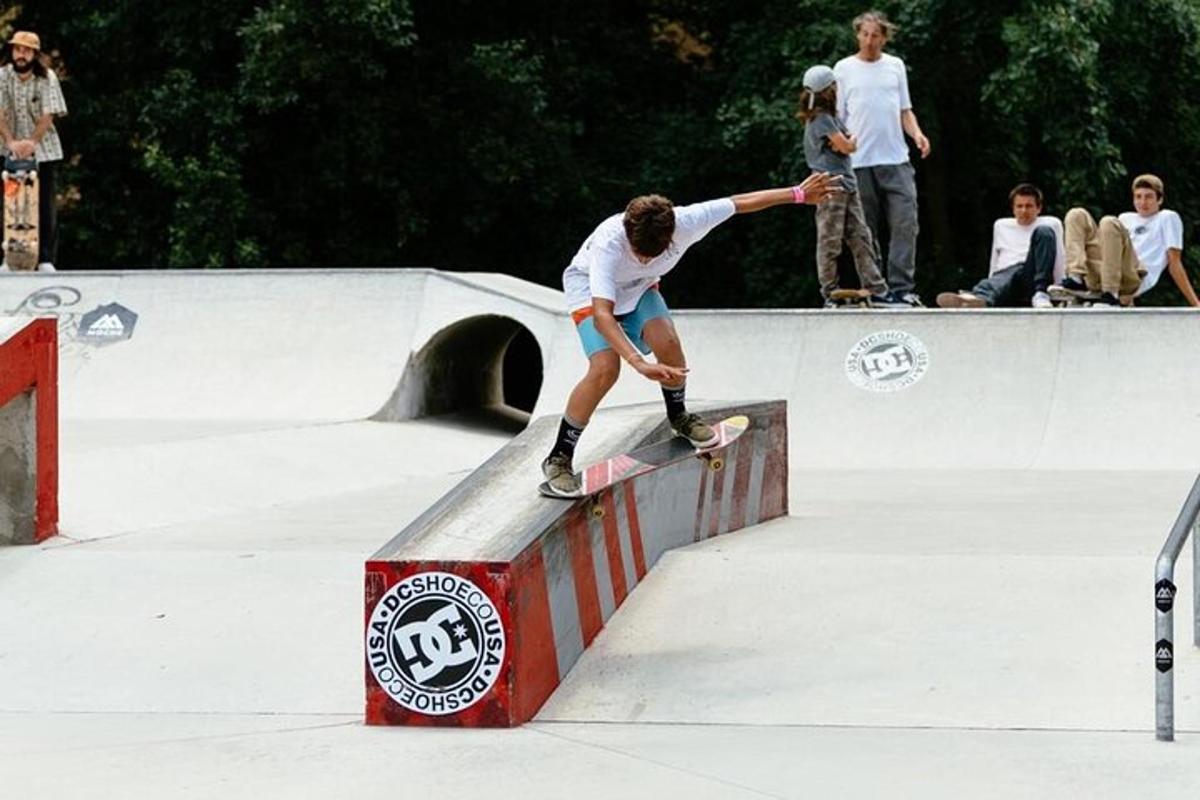 seorang lelaki menunggang papan selaju di atas rel di taman skate