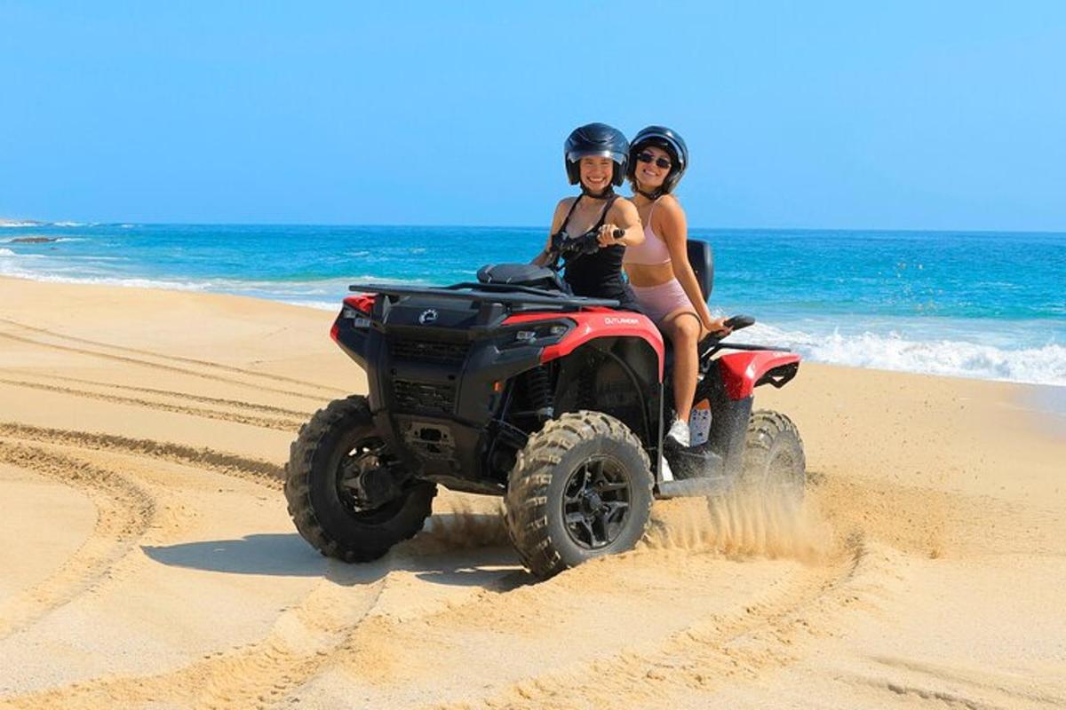 Dos personas montando un quad en la playa