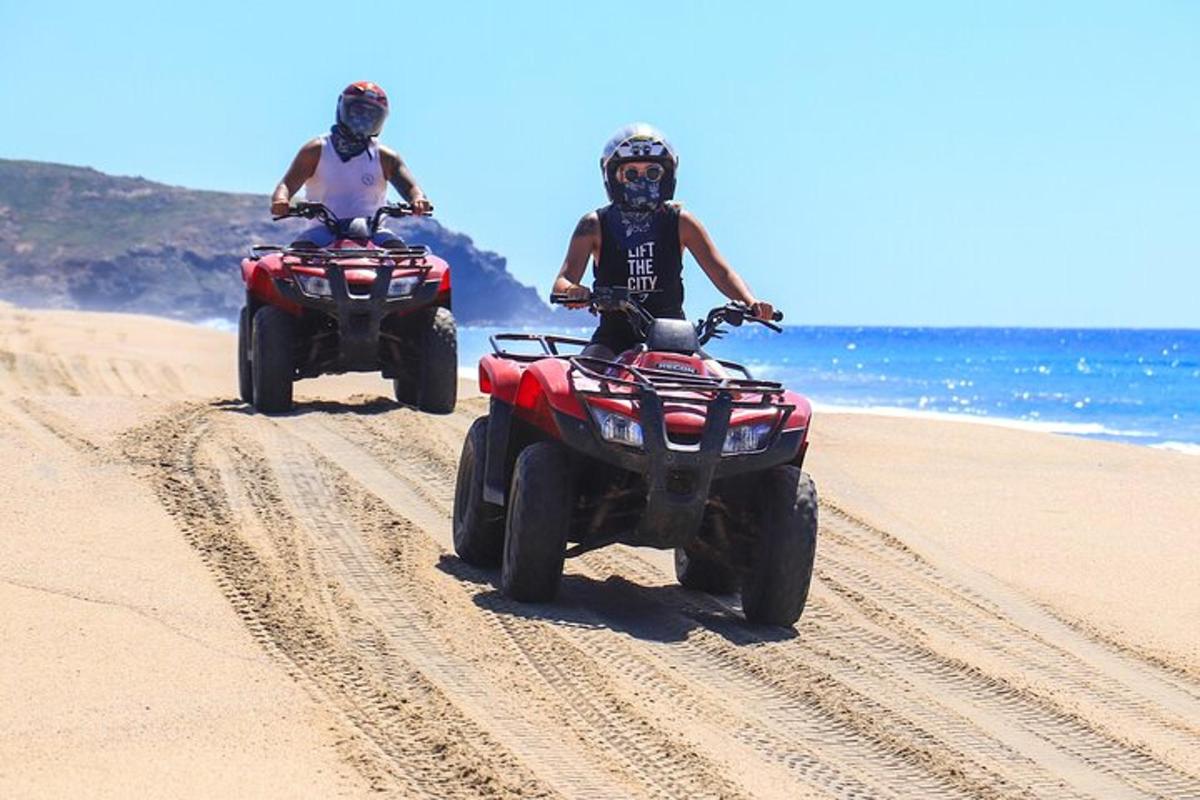 two people are riding atvs on the beach