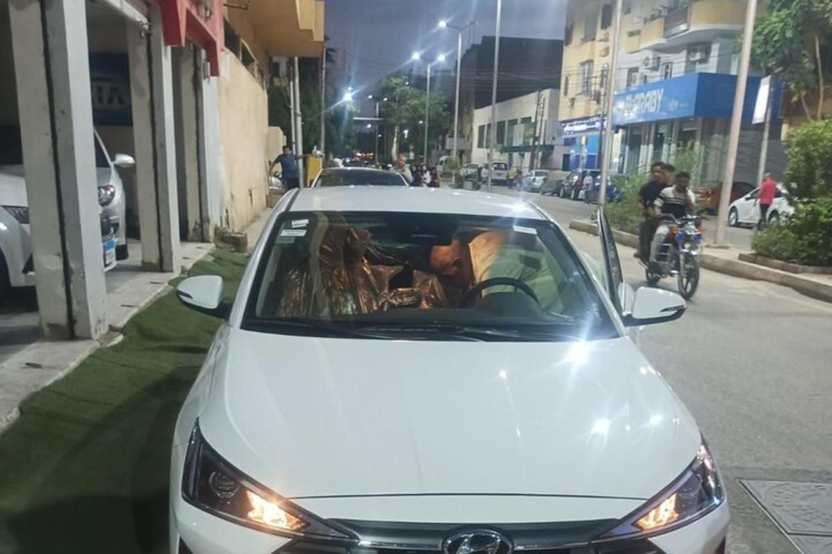um homem dirigindo um carro branco em uma rua