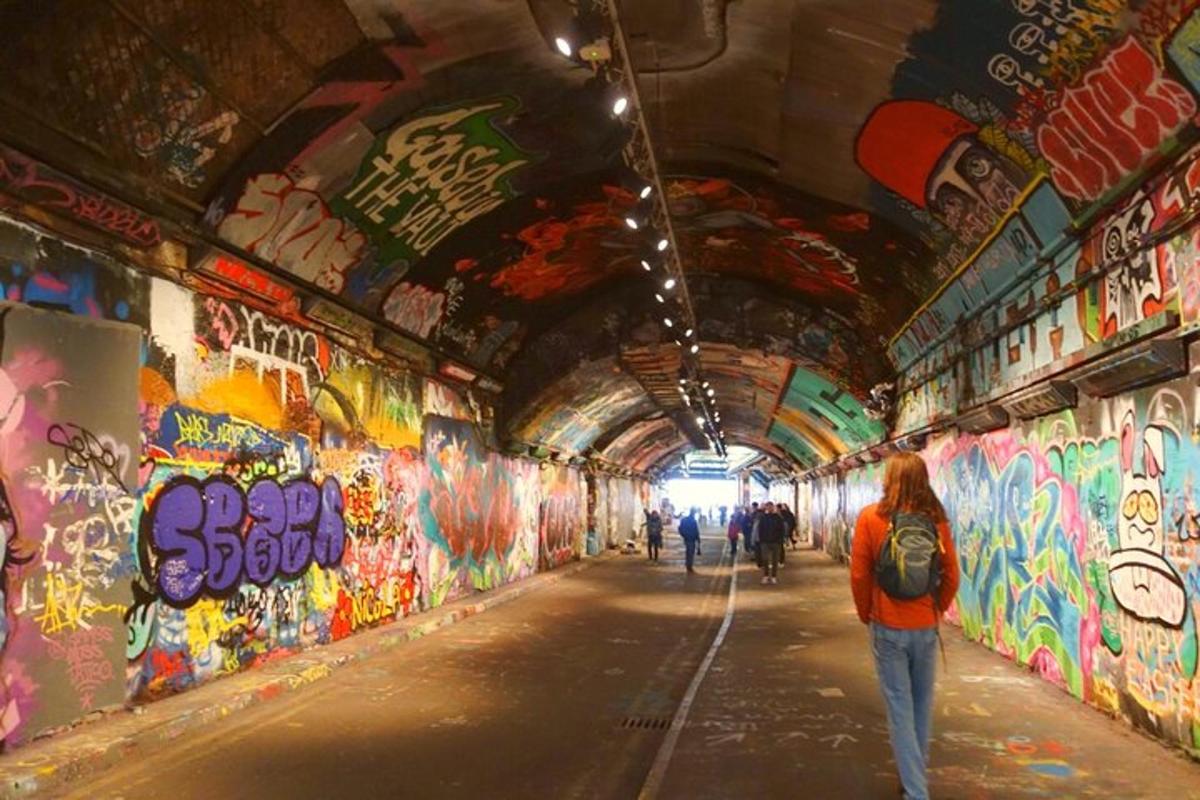 Una persona caminando por un túnel cubierto de grafitis.