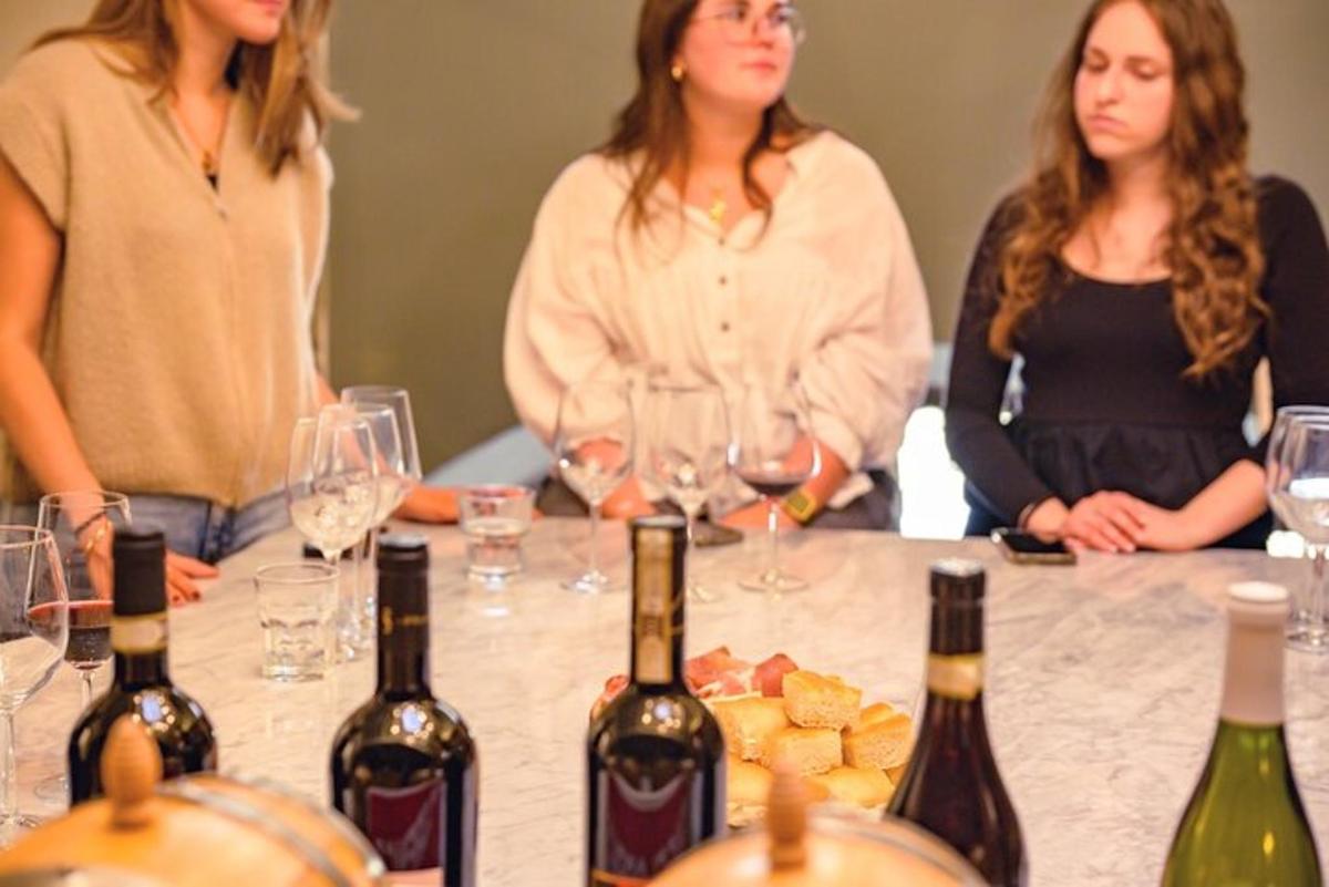 un grup de femei care stăteau în jurul unei mese cu sticle de vin